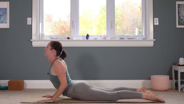 Woman on a yoga mat in Upward Dog as she practices Sun Salutations