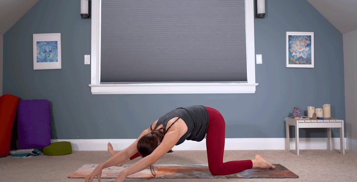 Woman practicing a half splits stretch with a side stretch on a yoga mat