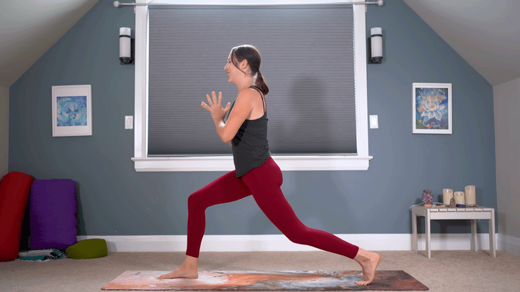 Woman practicing High Lunge on a yoga mat with her hands at her chest