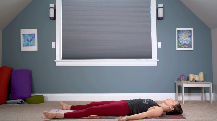 Woman lying in Savasana on her yoga mat