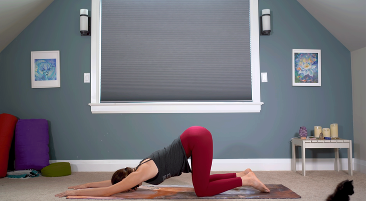 Yoga With Kassandra practicing a kneeling Puppy Pose on a yoga mat during a 30-minute practice