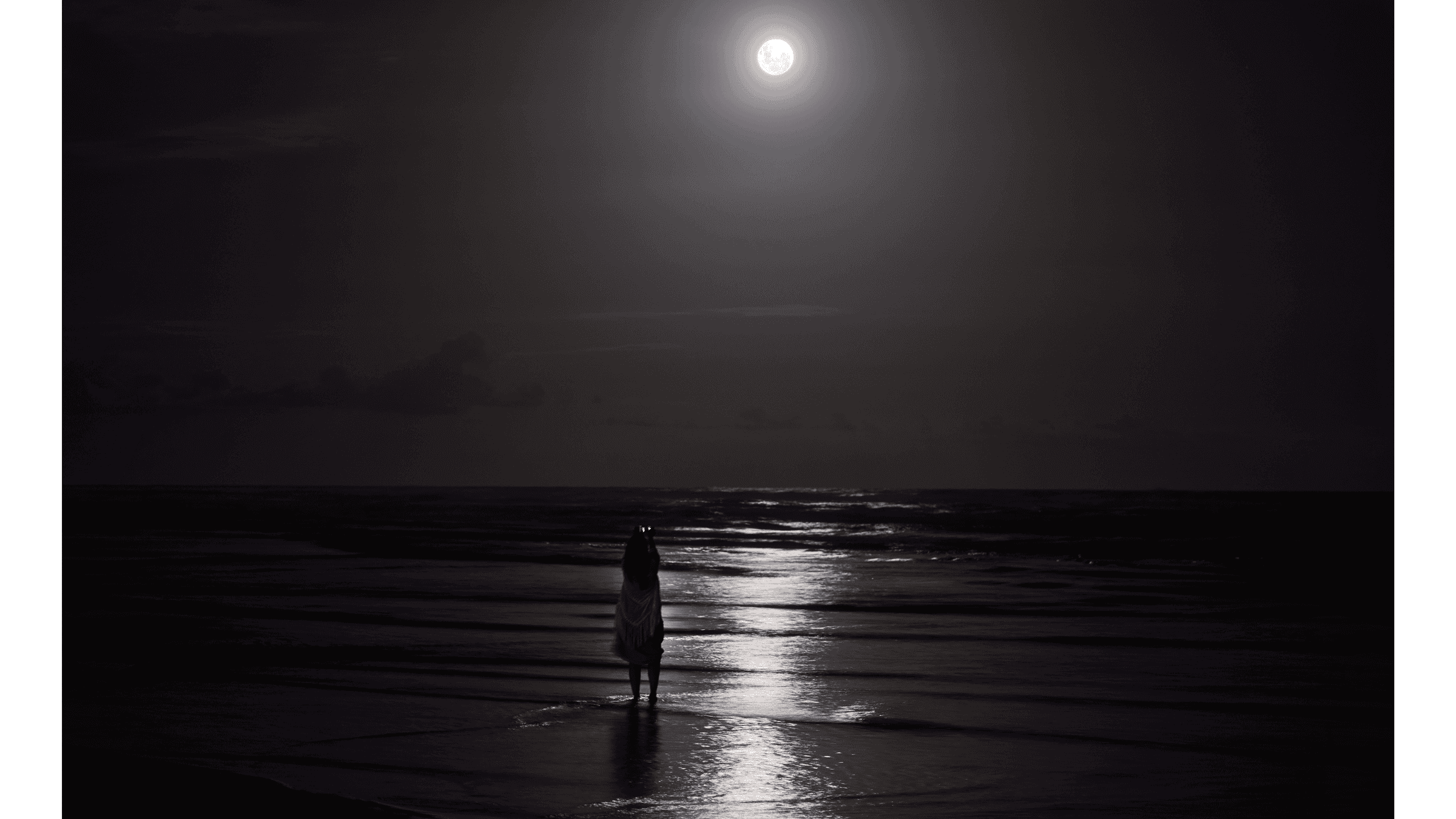 Woman standing on the beach in the light of the full Moon in Aquarius