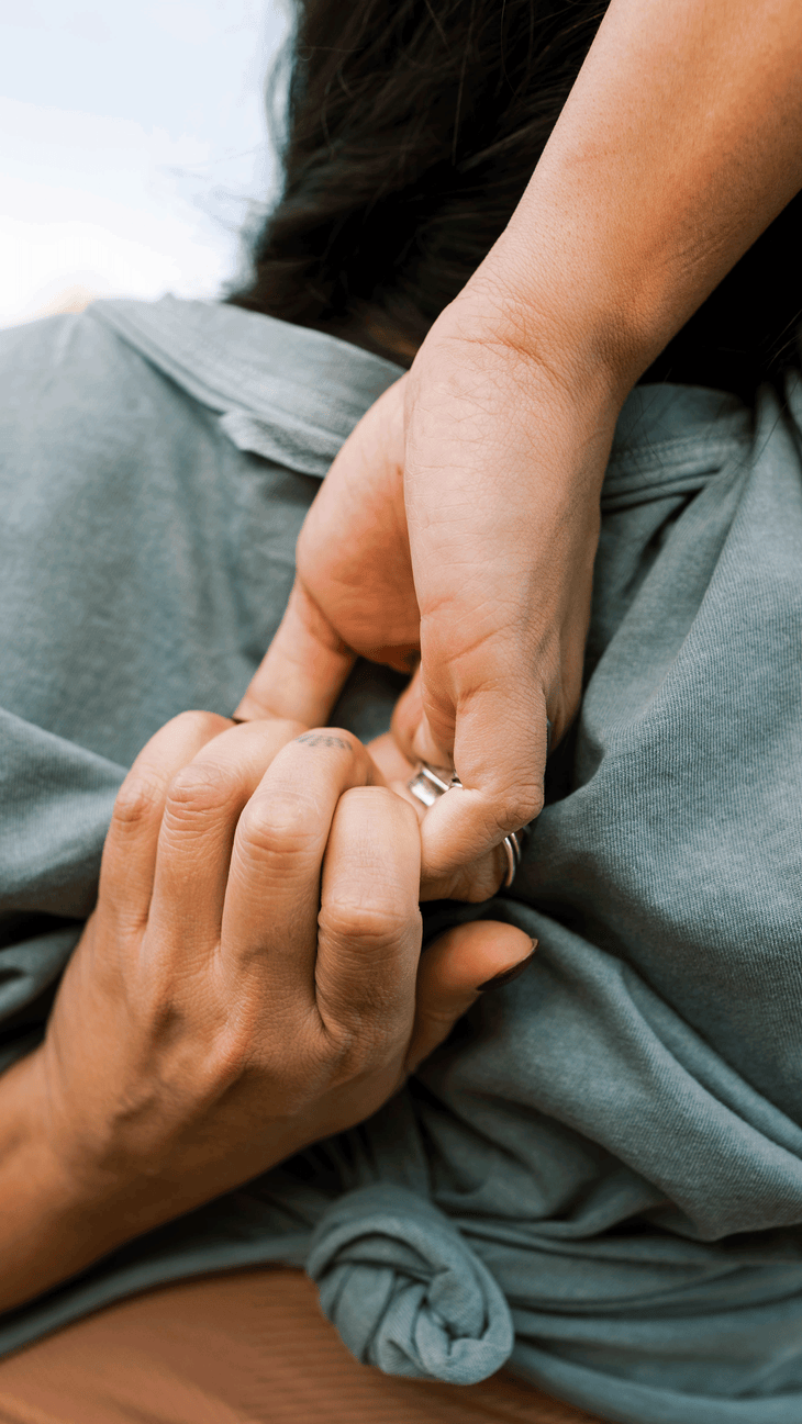 Close-up photo of hands gripping one another behind the back.