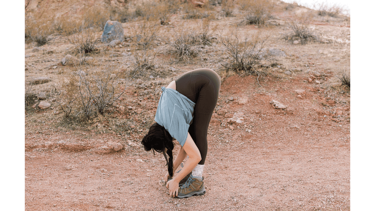 Woman hiker practicing standing forward bend on.a trail in the desert