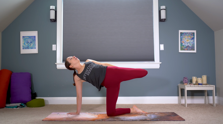 Woman kneeling on a yoga mat practicing a version of Half Moon Pose