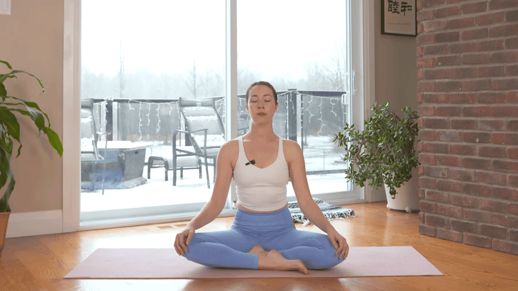 Yoga with Kassandra sitting cross-legged on a yoga mat at the end of a 10-minute morning yoga practice