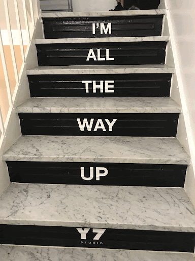 Image of staircase with printed text on each step that reads I'm all the way up and Y7 studio.