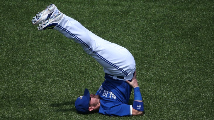 Josh Donaldson of the Toronto Blue Jays practices a shoulder stand pose on a baseball field