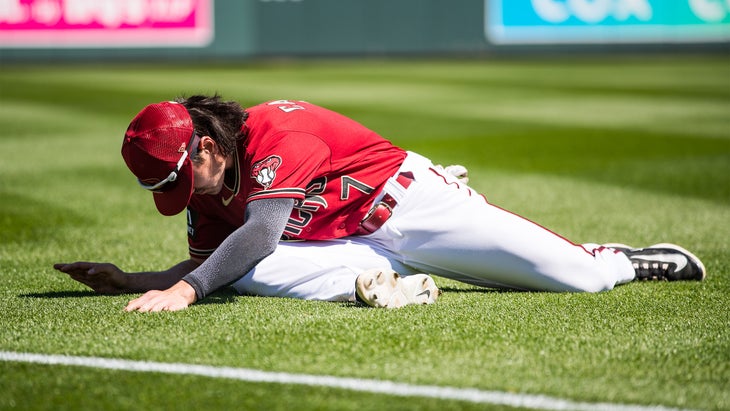 Corbin Carroll of the Arizona Diamondbacks practices a pigeon pose on a baseball field