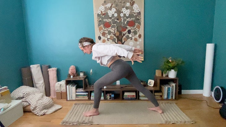 woman practicing yoga in her living room on a mat
