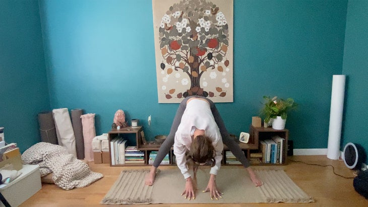 woman practicing a yoga pose bending over on a mat