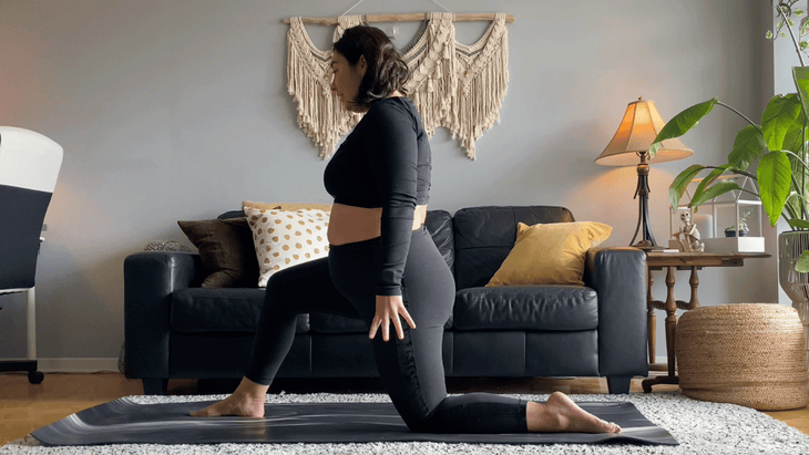 Woman kneeling on a yoga mat with one knee down and one foot forward