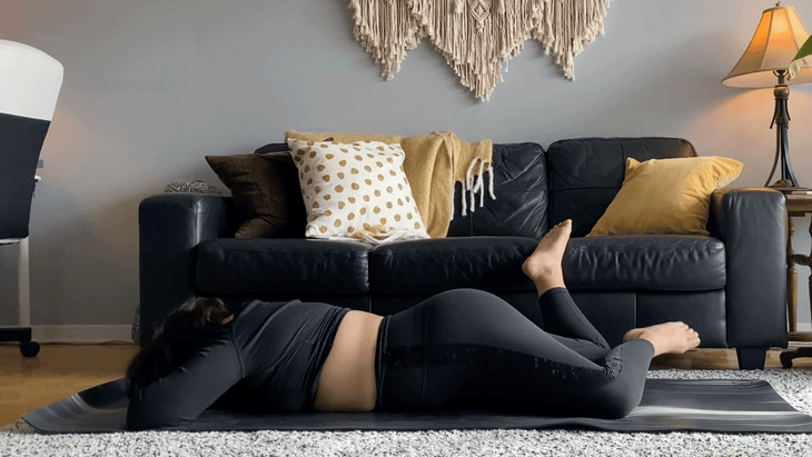 Woman lying on her belly on a yoga mat while bending her knees and letting them fall side to side