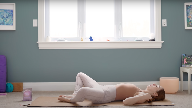 Woman lying on a yoga mat practicing yin yoga