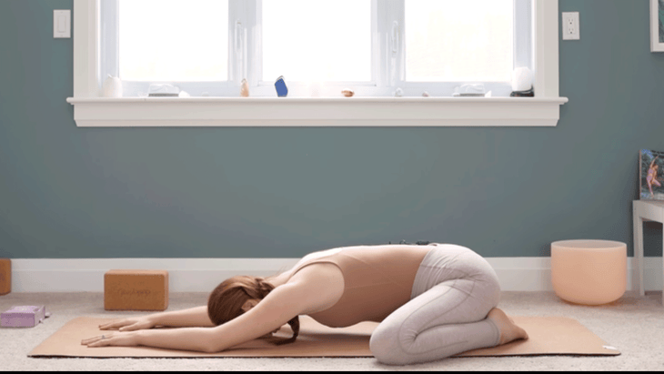 Yoga With Kassandra practicing Child's Pose or Balasana during a yin yoga for chakras class