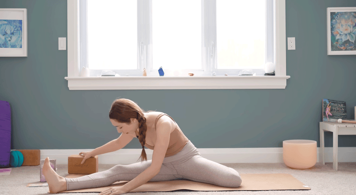Woman seated on a yoga mat practicing Deer Pose, a yin yoga stretch