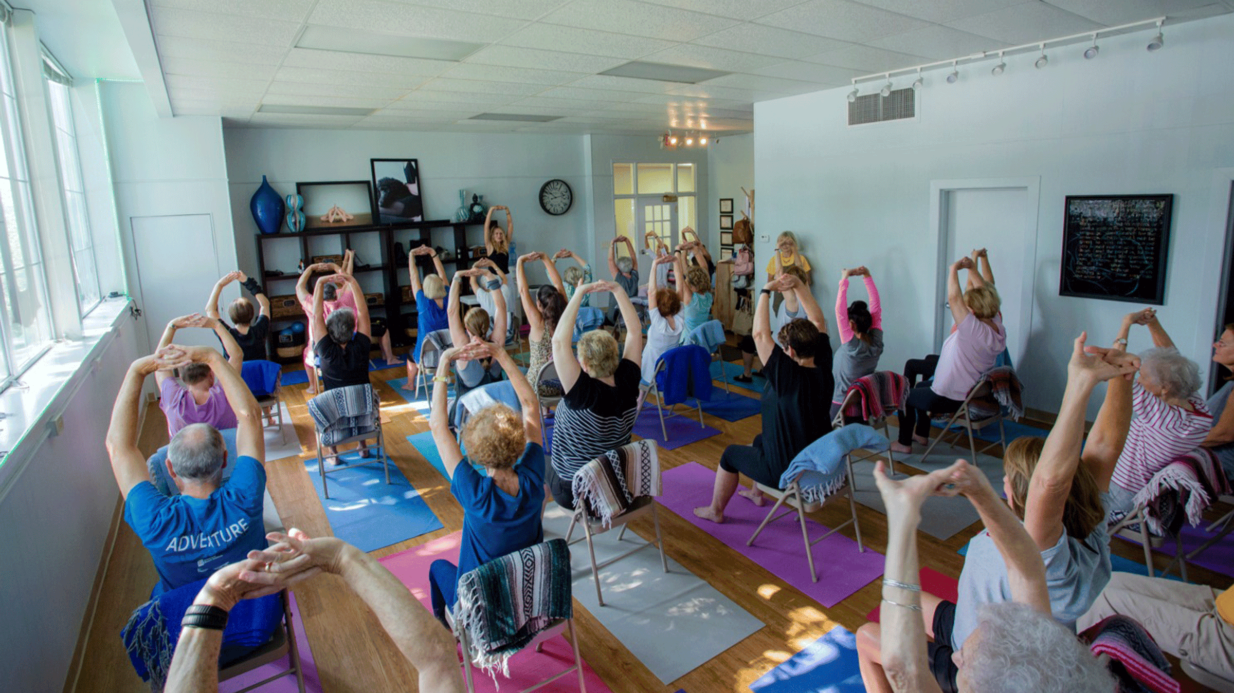 Seniors practicing chair yoga at Blue Yoga Nyla studio with teacher Stacey Reynolds