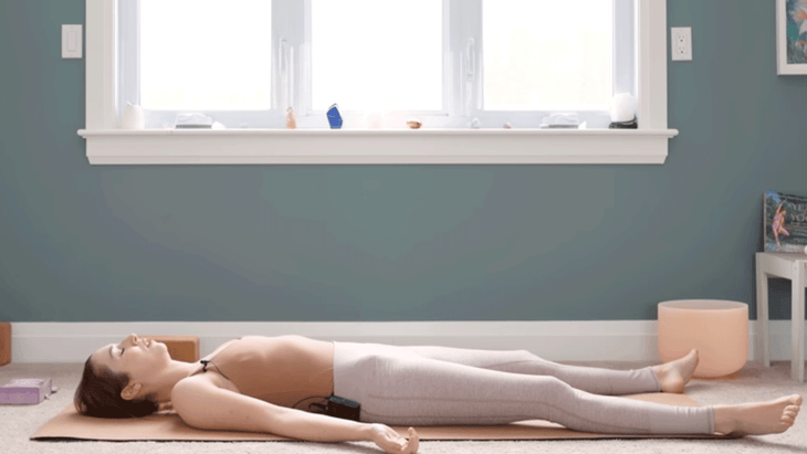 Yoga With Kassandra lying on a yoga mat in Savasana after practicing yoga for chakras