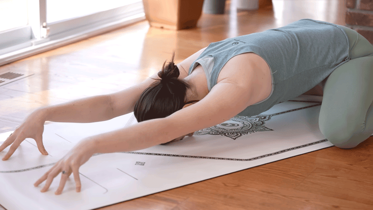 Woman in Child's Pose with her fingertips pressing into the mat