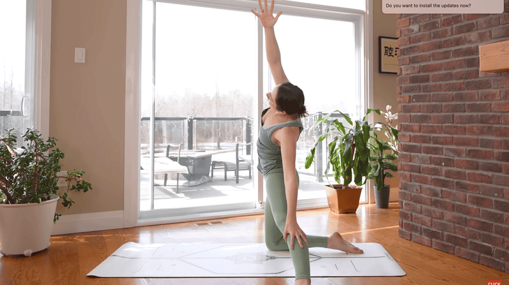 Woman practicing Gate Pose stretch on a yoga mat