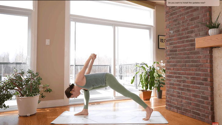 Woman practicing Humble Warrior with her hands clasped behind her back as she leans forward in a lunge.