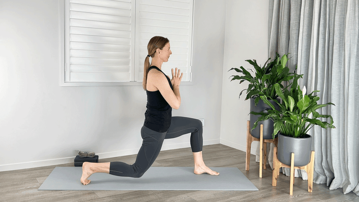 Woman practicing a High Lunge with her back knee bent 90 degrees and her back shin hovering just above the mat