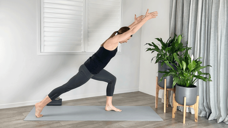 Woman in a lunge with her arms alongside her head as she leans forward with her chest toward her front thigh