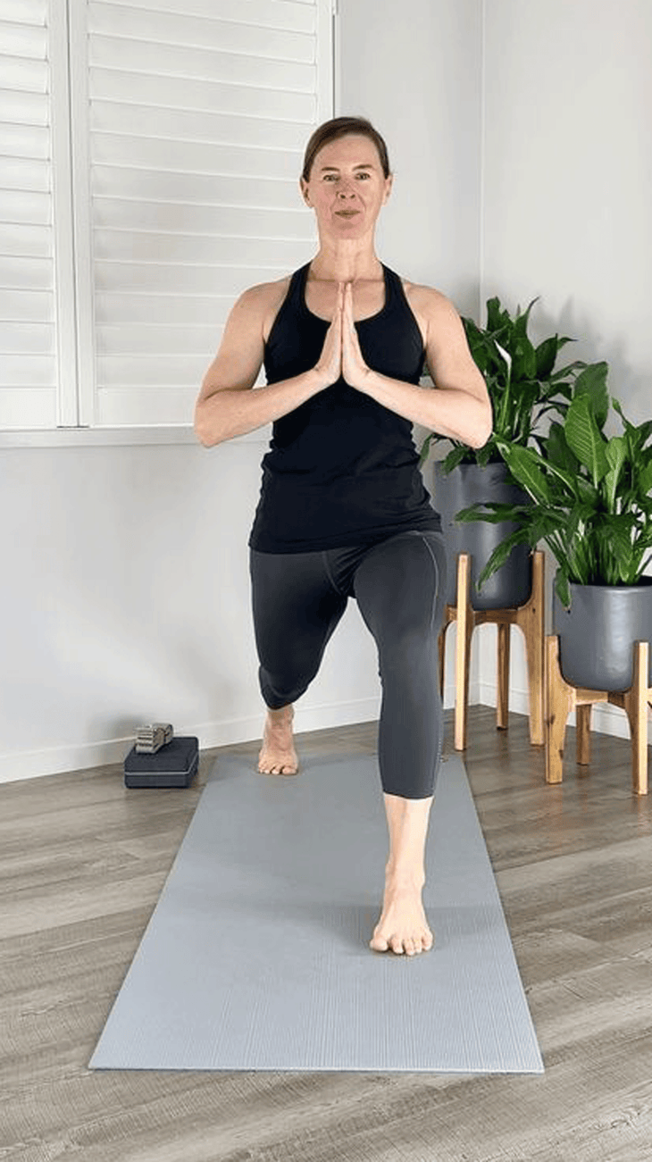 Woman practicing High Lunge with her hands in prayer at her chest