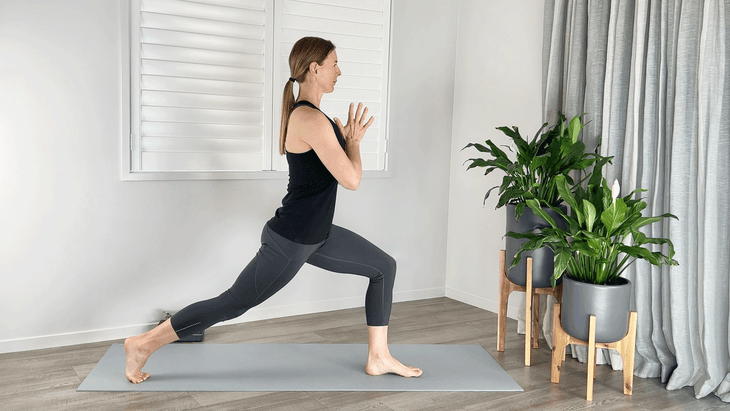 Woman practicing High Lunge on a yoga mat with her feet in a narrower stance than usual, as if she was on a tightrope