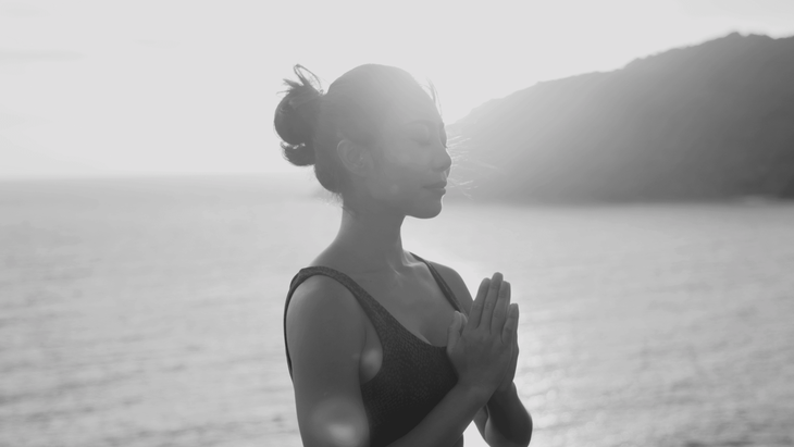 Woman standing near a cliff by the ocean slowing her breath as she learns how to overcome fear