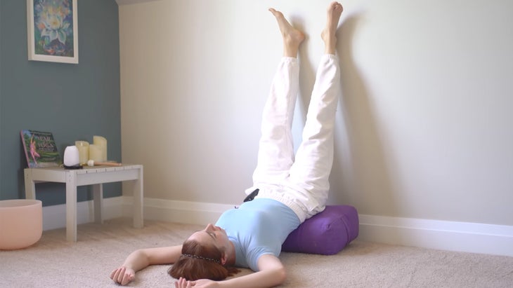 woman practicing yoga with legs up a wall in a traditional pose with legs together