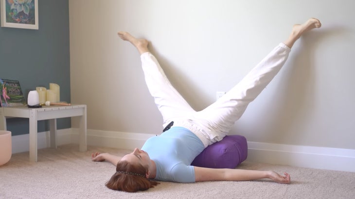 woman practicing yoga up a wall with her feet in a narrow split