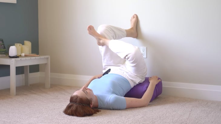woman practicing yoga up a wall with one foot on the wall