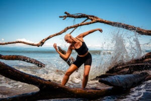 Image of yoga teacher Kirin Power posing in front of the ocean.