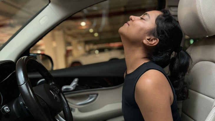 woman practicing yoga in her car stretching her net upwards