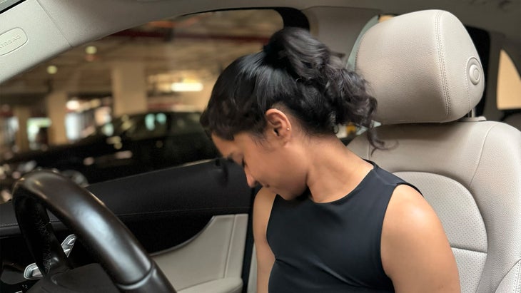 woman practicing yoga in her car rolling her neck