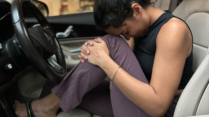 woman practicing yoga in her car pulling her left knee to her chest