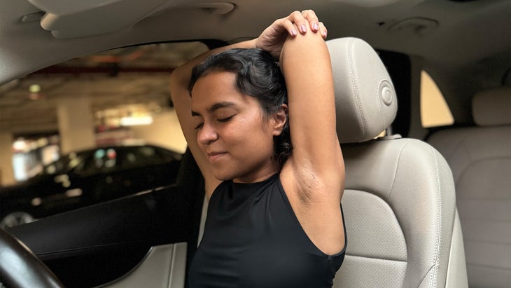 woman practicing yoga in her car crossing her arms over her head