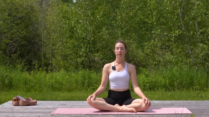 woman practicing yoga on mat outdoors in seated pose