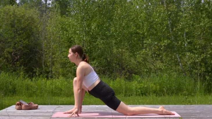 woman practicing yoga on mat outdoors in low lunge