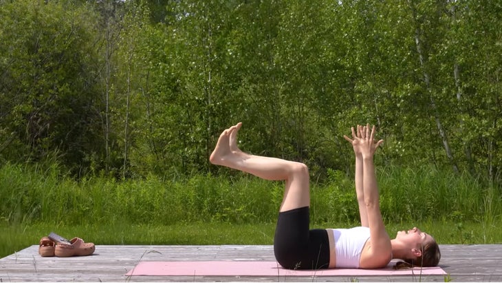 woman practicing yoga on mat outdoors in extended tabletop