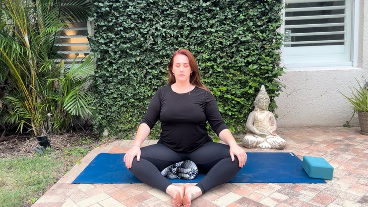 woman practicing yoga sitting crosslegged on a mat