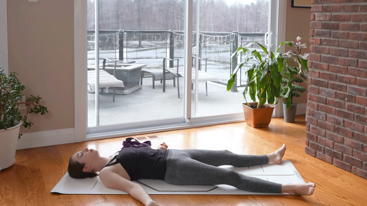 Woman practicing stretches for sleep and lying on her back in Savasana