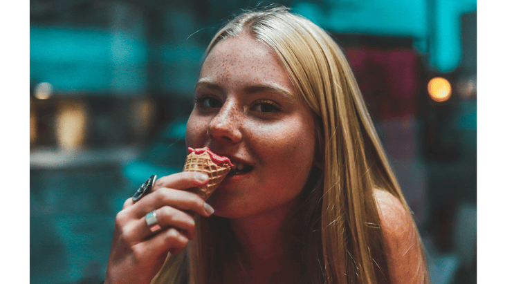 Woman holding a sugar ice cream cone with sorbet slowly eating it