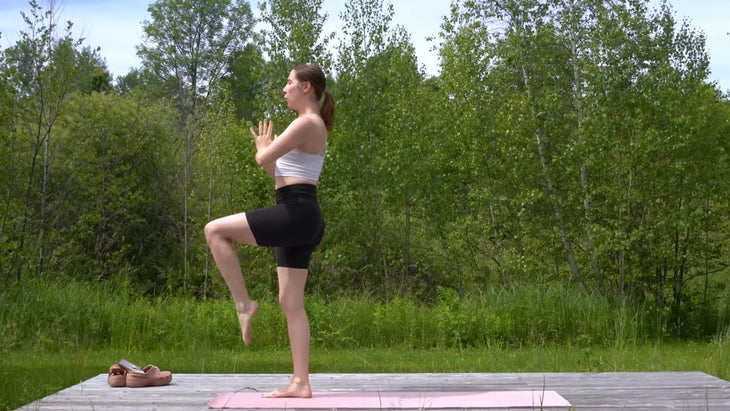 woman outdoors on a yoga mat in warrior pose