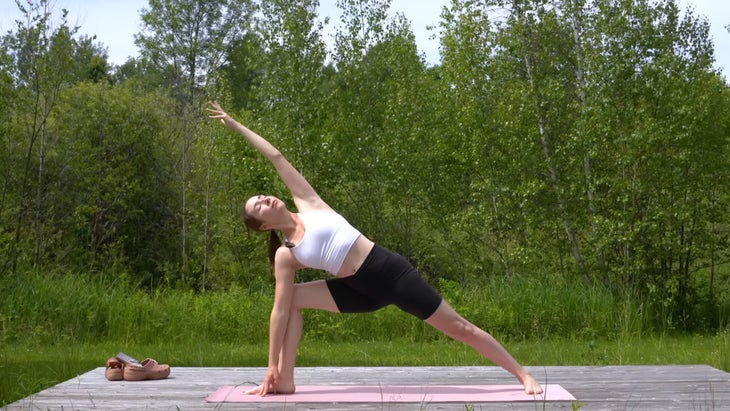 woman outdoors on a yoga mat in an extended side angle pose