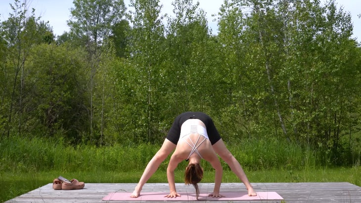 woman outdoors on a yoga mat in a forward bend