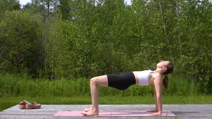 woman outdoors on a yoga mat in reverse tabletop pose