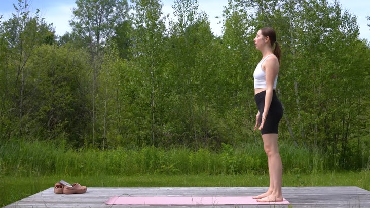 woman outdoors on a yoga mat standing in mountain pose