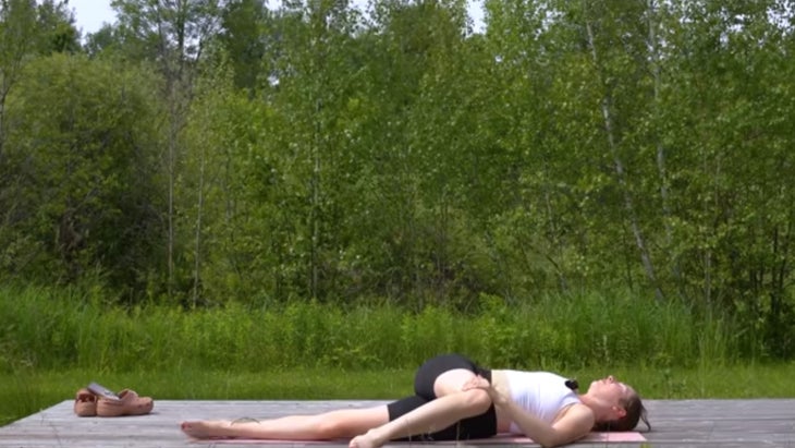 woman outdoors on a yoga mat finishing a 15-minute morning yoga practice